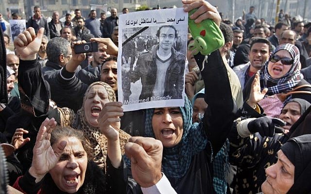 Egyptian relatives of Mohammed el-Gindy, a 28-year-old activist, who died of wounds sustained during clashes near the presidential palace, display his picture as they shout anti-president Morsi slogans during his funeral procession in Tahrir Square, Cairo, on February 4. (photo credit: Amr Nabil/AP) Egyptian relatives of Mohammed el-Gindy, a 28-year-old activist, who died of wounds sustained during clashes near the presidential palace, display his picture as they shout anti-president Morsi slogans during his funeral procession in Tahrir Square, Cairo, on February 4. (photo credit: Amr Nabil/AP)