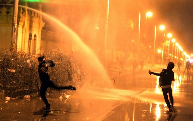 Egyptian protesters throw stones while security police fire water cannon in Cairo, Egypt, Monday, Feb. 11, 2013. (photo credit: AP/Khalil Hamra)