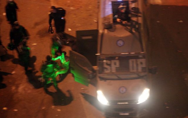 Egyptian riot police beat a man, illuminated by the green light of a protester's laser, after stripping him, and before dragging him into a police van, during clashes next to the presidential palace in Cairo, Friday, Feb. 1, 2013. Protesters denouncing Egypt's Islamist president hurled stones and firebombs through the gates of his palace gates on Friday, clashing with security forces who fired tear gas and water cannons, as more than a week of political violence came to Mohammed Morsi's symbolic doorstep for the first time. (Photo credit: AP/Khalil Hamra) Egyptian riot police beat a man, illuminated by the green light of a protester's laser, after stripping him, and before dragging him into a police van, during clashes next to the presidential palace in Cairo, Friday, Feb. 1, 2013. Protesters denouncing Egypt's Islamist president hurled stones and firebombs through the gates of his palace gates on Friday, clashing with security forces who fired tear gas and water cannons, as more than a week of political violence came to Mohammed Morsi's symbolic doorstep for the first time. (Photo credit: AP/Khalil Hamra)