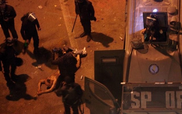 Egyptian riot police beat 48-year-old Hamada Saber after stripping him, and before dragging him into a police van, during clashes next to the presidential palace in Cairo earlier this month (photo credit: AP/Khalil Hamra) Egyptian riot police beat 48-year-old Hamada Saber after stripping him, and before dragging him into a police van, during clashes next to the presidential palace in Cairo earlier this month (photo credit: AP/Khalil Hamra)