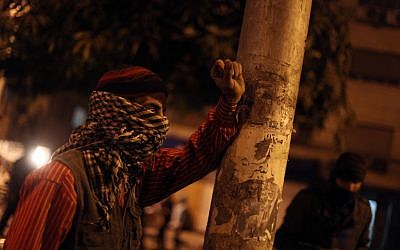 An Egyptian protester covers his face as he stands during clashes with riot police, not seen, near the presidential palace in Cairo, Egypt, Monday, Feb. 11, 2013. (photo credit: AP/Khalil Hamra)
