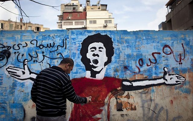An Egyptian activist paints a mural depicting a slain activist with Arabic that reads 'Why did you do this? This is very sad,' on a wall in Tahrir Square in Cairo, Egypt, on February 19, 2013. (photo credit: Nasser Nasser/AP)
