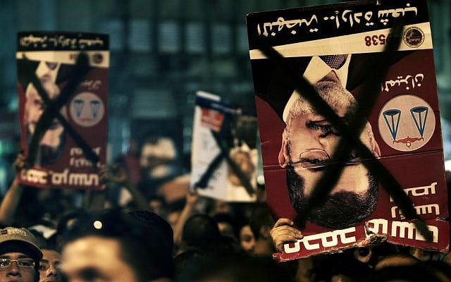 Egyptians chant slogans and hold defaced posters with the photo of President Mohammed Morsi in Tahrir Square, Cairo, May 2012 (photo credit: Fredrik Persson/AP)