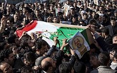 Iranian mourners carry the flag draped coffin of Gen. Hassan Shateri, shown in the poster, in Tehran. Prominent Iranian politicians and clerics led mourners at a funeral Thursday for a senior commander of the country's powerful Revolutionary Guards who was killed this week while traveling from Syria to Lebanon, local media said. (AP Photo/Fars News Agency, Saeed Kariminejad