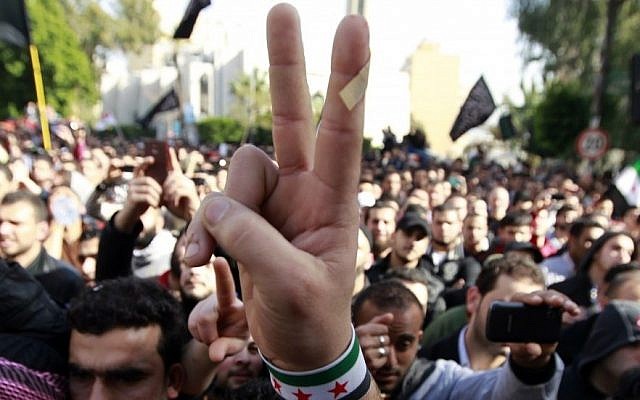 An anti-Syrian regime protester flashes the victory sign with a Syrian revolutionary flag bracelet as he listens to Sheikh Ahmad al-Assir, unseen, a hard-line Sunni Lebanese cleric, deliver a sermon in support of the opposition after Friday prayers in Beirut, Lebanon, February 8, 2013 (photo credit: AP/Bilal Hussein)