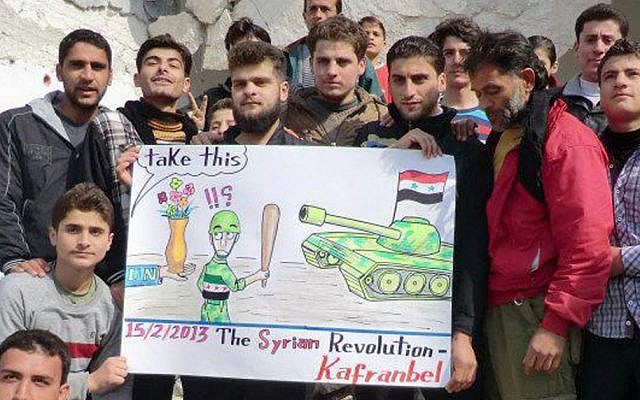 Anti-regime protesters hold a caricature placard during a demonstration in Idlib province, Syria, on Friday (photo credit: AP/Edlib News Network ENN) Anti-regime protesters hold a caricature placard during a demonstration in Idlib province, Syria, on Friday (photo credit: AP/Edlib News Network ENN)