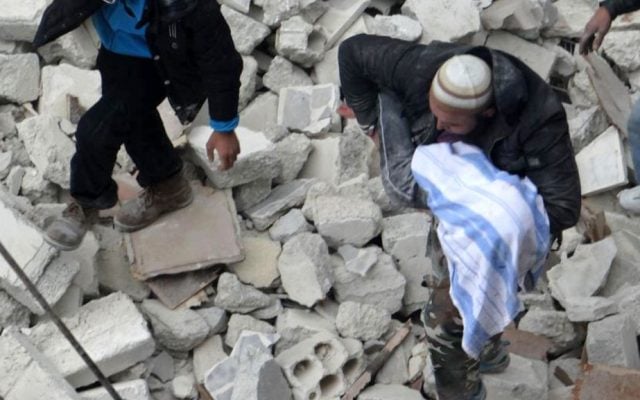 A man carries a body among ruins in the Syrian city of Aleppo, Sunday (photo credit: Aleppo Media Center AMC/AP)