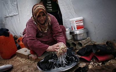 A displaced Syrian woman washes some clothes in front of her tent in the Azaz camp for displaced people, north of Aleppo province, Syria, Monday, Feb. 18, 2013 (photo credit: AP/Manu Brabo)