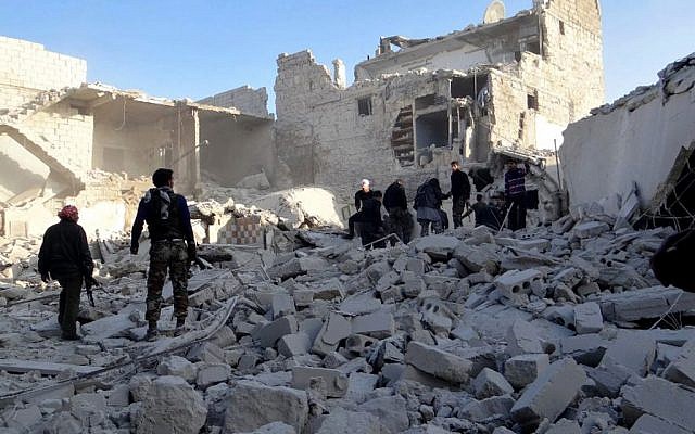 Syrian rebels stand in the rubble of buildings damaged by government airstrikes, in Aleppo, Syria, Wednesday, February 13, 2013. (photo credit: AP/Aleppo Media Center AMC) Syrian rebels stand in the rubble of buildings damaged by government airstrikes, in Aleppo, Syria, Wednesday, February 13, 2013. (photo credit: AP/Aleppo Media Center AMC)