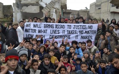 This citizen journalism image provided by Edlib News Network, ENN, which has been authenticated based on its contents and other AP reporting, shows anti-Syrian regime protesters flashing the victory sign as they hold a banner during a demonstration in Idlib province, northern Syria, Friday. (AP Photo/Edlib News Network ENN)
