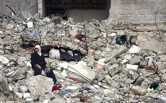A Syrian woman sits on the ruins of her house, which was destroyed in a recent government airstrike that killed 11 members of her family, in Aleppo, Syria, on Thursday (photo credit: AP/Abdullah al-Yassin)