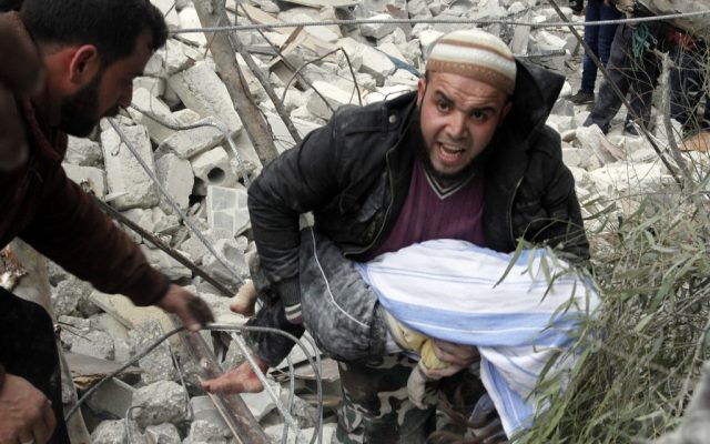 A Syrian man carries a child's body after a government airstrike hit the neighborhood of Ansari, in Aleppo, Syria on Sunday, February 3, 2013. (AP Photo/Abdullah al-Yassin)