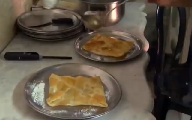 Adding sugar syrup to the finished pastry (photo credit: YouTube screenshot)