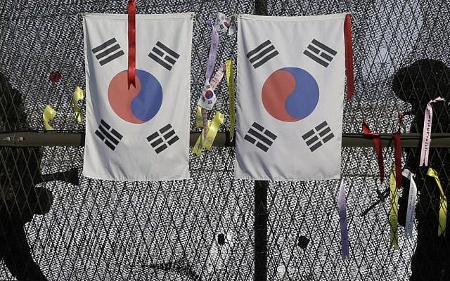 South Korean army soldiers patrol by the national flags and ribbons, wishing for the reunification of the two Koreas, attached on the barbed-wire fence at the Imjingak Pavilion near the border village of Panmunjom, which has separated the two Koreas since the Korean War, in Paju, north of Seoul, South Korea, Wednesday, Feb. 13, 2013 (photo credit: AP/Lee Jin-man)