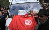 Protesters gather with a Tunisian flag around an ambulance carrying the body of opposition leader Chokri Belaid in Tunis, Wednesday, Feb. 6 (photo credit: AP/Amine Landoulsi)