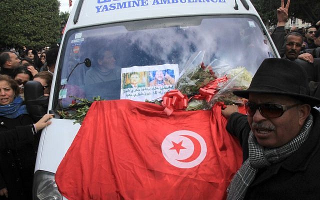 Protesters gather with a Tunisian flag around an ambulance carrying the body of opposition leader Chokri Belaid in Tunis, Wednesday, Feb. 6 (photo credit: AP/Amine Landoulsi) Protesters gather with a Tunisian flag around an ambulance carrying the body of opposition leader Chokri Belaid in Tunis, Wednesday, Feb. 6 (photo credit: AP/Amine Landoulsi)