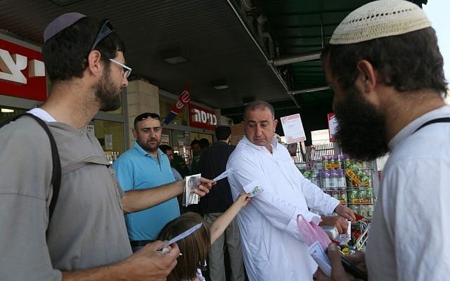 Members of Eretz Shalom movement giving candy to Arab shoppers as they mark the last Friday prayers of Ramadan, at the Rami Levy supermarket in Gush Etzion on August 17, 2012. (photo credit: Nati Shohat/Flash90)