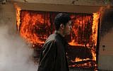 An Egyptian man walks on the grounds of a police officer's club as a fire set by protesters burns in Cairo, Egypt, Saturday, March 9, 2013 (photo credit: AP/Ahmed Gomaa)