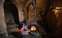 Nihal, 9, puts olive tree branches inside a wooden stove at an underground Roman tomb which his family uses for shelter from government shelling and airstrikes, at Jebel al-Zawiya, in Idlib province, Syria, on Thursday. (photo credit: AP/Hussein Malla)