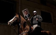 A Druze man holds aloft a machete and a portrait of Syrian President Bashar Assad during a rally in the village of Majdal Shams marking Syrian Independence Day, April 17, 2012 (photo credit: Matanya Tausig/Flash90)