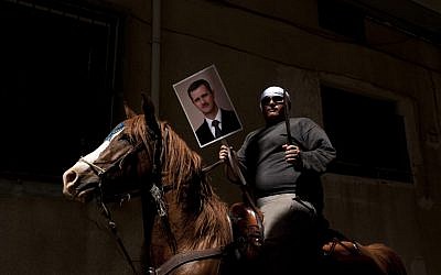 A Druze man holds aloft a machete and a portrait of Syrian President Bashar Assad during a rally in the village of Majdal Shams marking Syrian Independence Day, April 17, 2012 (photo credit: Matanya Tausig/Flash90)