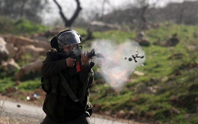 A soldier fires a smoke grenade at a demonstration at Birzeit University, February 15 (photo credit: Issam Rimawi/ Flash90)