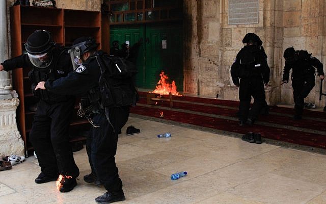An Israeli policeman puts out flames on his foot from a molotov cocktail thrown at him from inside al-Aqsa Mosque on Friday. Behind him, a second petrol bomb burns (Photo credit: Sliman Khader/Flash 90) An Israeli policeman puts out flames on his foot from a molotov cocktail thrown at him from inside al-Aqsa Mosque on Friday. Behind him, a second petrol bomb burns (Photo credit: Sliman Khader/Flash 90)