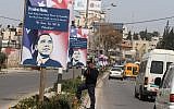 A Palestinian policeman stands next to a poster informing US President Barack Obama, "We have no 3G in Palestine," in the West Bank city of Ramallah in 2013 (photo credit: Issam Rimawi/Flash90)