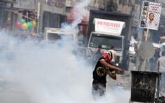 Palestinian protesters throw stones at an Israeli military tower during a rally marking Land Day at the main entrance to the Qalandiya checkpoint, in the West Bank, March 2013. (photo credit: Issam Rimawi/Flash90)