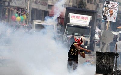Palestinian protesters throw stones at an Israeli military tower during a rally marking Land Day at the main entrance to the Qalandiya checkpoint, in the West Bank, March 2013. (photo credit: Issam Rimawi/Flash90)