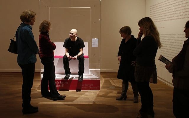 Visitors surround Ido Porat, the first person acting as the 'Jew in a glass box', on the first day of the exhibition 'The Whole Truth … everything you always wanted to know about Jews' at the Jewish Museum in Berlin,  March 22, 2013 (photo credit: AP/Markus Schreiber)