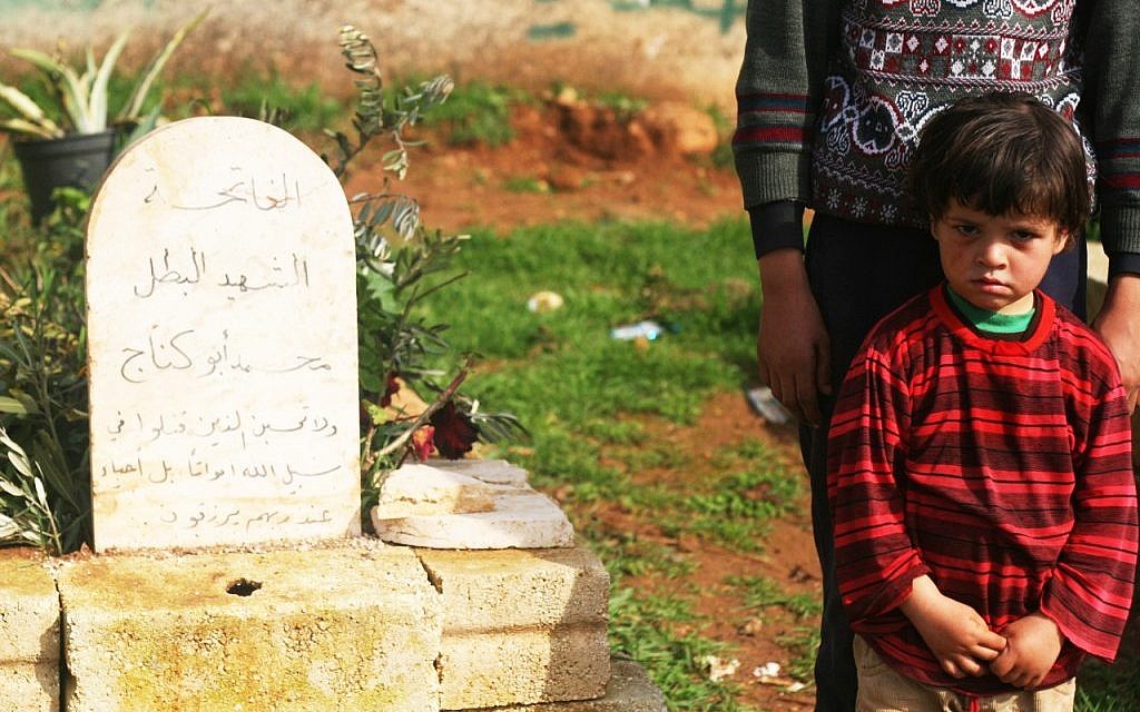 A young boy beside the grave of his relative, a fallen FSA soldier, in Qalaat al-Madik (photo: Eliyahu Kamisher)