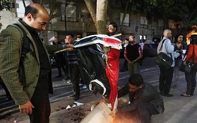 Egyptian protesters burn the Libyan flag during a protest in front of the Libyan embassy, in Cairo, Egypt, Monday, March 11, 2013 (photo credit: AP/Mohammed Abu Zaid)