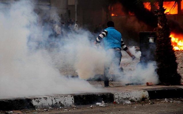 An Egyptian protester throws a teargas canister back toward police during clashes in Port Said on Monday (photo credit: Ahmed Ramadan/AP)