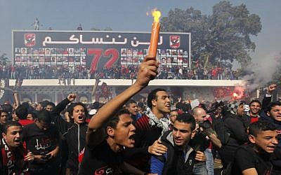Egyptian soccer fans of Al-Ahly club celebrate in front of their club in Cairo, Egypt, Saturday. An Egyptian court confirmed death sentences against 21 people for their role in a deadly 2012 soccer riot that killed more than 70 people in the city of Port Said. Banner at background showing some pictures of the victims with Arabic that reads, "we will never forget you." (AP Photo/Amr Nabil)