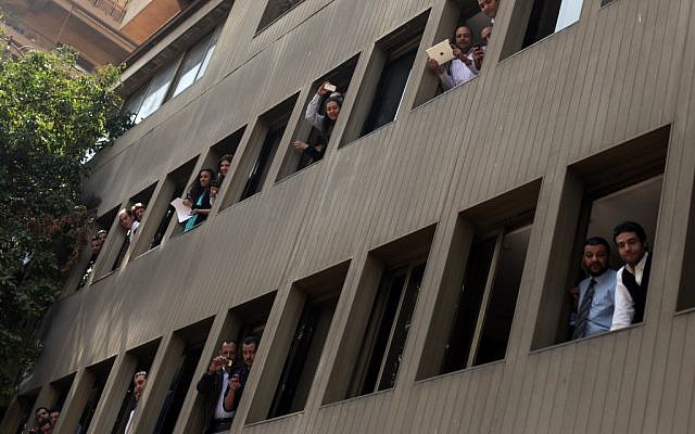 Egyptians look at police officers as they arrest Ahmed Qaddaf al-Dam, cousin of Libya’s former dictator Moammar Gadhafi, not pictured, after being arrested in Cairo, Egypt, on March 19. 2013. (photo credit: AP Photo/Khalil Hamra)
