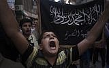 In this Friday, Sept. 21, 2012 file photo, a Syrian boy shouts slogans against the regime in front of a flag of the armed Islamic opposition group, the Nusra front, during a demonstration in the Bustan al-Qasr neighborhood of Aleppo, Syria (photo credit: Manu Brabo/AP)