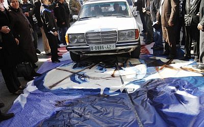 A man drives his car over a poster of US President Barack Obama in the West Bank city of Bethlehem, Monday, March 18, 2013. (photo credit: AP/Nasser Shiyoukhi)