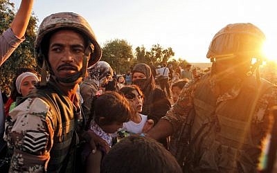 File: In this Wednesday, Sept. 5, 2012 photo, newly-arrived Syrian refugee families receive food from the Jordanian military after they crossed the border from Tal Shehab in Syria, through the Al Yarmouk River valley, into Thnebeh town, in Ramtha, Jordan. (AP/Mohammed Hannon)