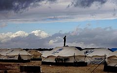 A Syrian refugee stands on top of a water tank at the Zaatari refugee camp, near the Jordanian-Syrian border, in Mafraq, Jordan, in January 2013 (photo credit: AP/Mohammad Hannon)