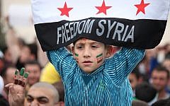 A Syrian boy waves the Syrian revolutionary flag during a commemorative celebration of the second anniversary of the Syrian revolution, in Amman, Jordan, March 16, 2013. (photo credit: AP/Mohammad Hannon)