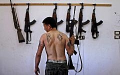 A Syrian rebel in an Aleppo arsenal (photo credit: AP/Muhammed Muheisen)