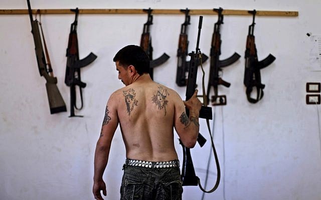 A Syrian rebel in an Aleppo arsenal (photo credit: AP/Muhammed Muheisen)