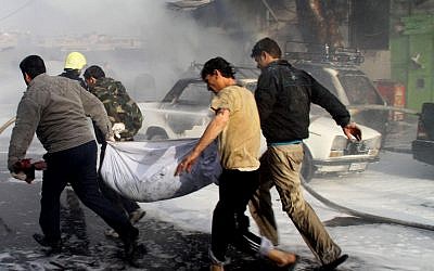 In this photo released by the Syrian official news agency SANA, Syrian citizens carry a dead body, at the scene where two mortar rounds exploded near an orphanage, at al-Boukhtyar area, in Damascus (photo credit: AP/SANA)
