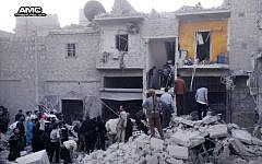Syrian citizens stand on the rubble of houses that were destroyed by government airstrikes in Aleppo, Syria, earlier this month (photo credit: AP/Aleppo Media Center)