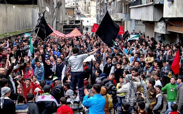 Anti-Syrian regime protesters holding banners and chanting slogans, during a demonstration in the neighborhood of Bustan Al-Qasr in Aleppo, Syria on Friday. (photo credit: AP/Aleppo Media Center AMC)