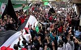 In this citizen journalism image provided by Aleppo Media Center AMC which has been authenticated based on its contents and other AP reporting, anti-Syrian regime protesters raise up their hands as they wave Syrian revolutionary flags during a protest to mark the second anniversary of the their uprising, in Aleppo, Syria, Friday March 15, 2013. The chief of Syria's main, western-backed rebel group marked the second anniversary of the start of the uprising against President Bashar Assad on Friday by pledging to fight until the "criminal" regime is gone. (AP Photo/Aleppo Media Center, AMC)