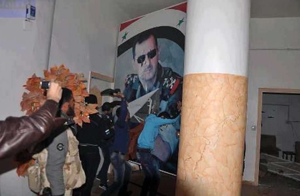 Syrians tearing down a huge poster of President Bashar Assad and hitting it with their shoes, in Raqqa, Syria, on Monday, March. 4, 2013. The picture was reportedly taken inside the Air Force Intelligence headquarters in Raqqa. (photo credit: AP Photo/Coordination Committee In Kafr Susa)