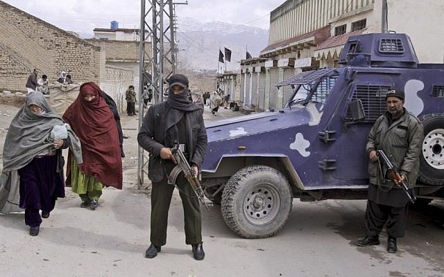 Pakistani security men stand alert as women from Pakistani Hazara Shi'ite community walk past during Friday prayers outside a Shi'ite mosque in Quetta, Pakistan. (AP Photo/Arshad Butt)