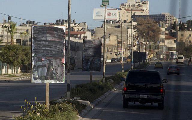 Signs that once had an image of President Barack Obama are painted over with black on Thursday. (photo credit: AP/Carolyn Kaster)